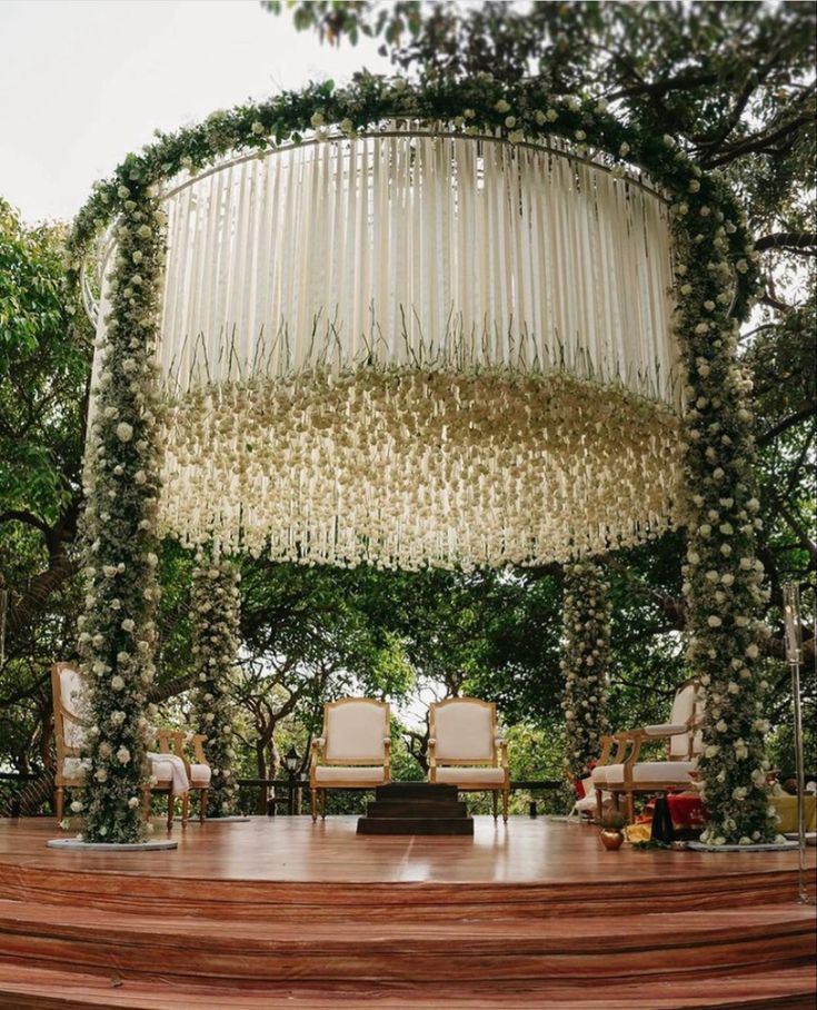 Elegant outdoor wedding ceremony stage with a circular arch decorated with hanging white flowers and greenery.